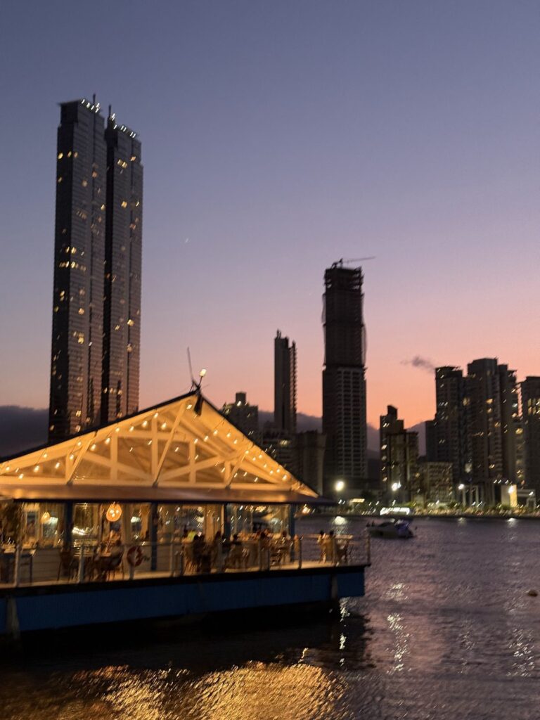 The towers of Barra Sul at dusk, seen across the water with boats in the foreground