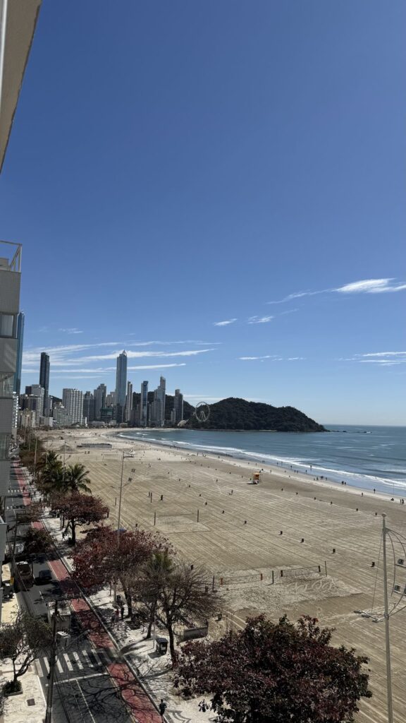 Praia Central and Avenida Atlântica seen from a high floor, with palm trees, the cycle path and the wide beach